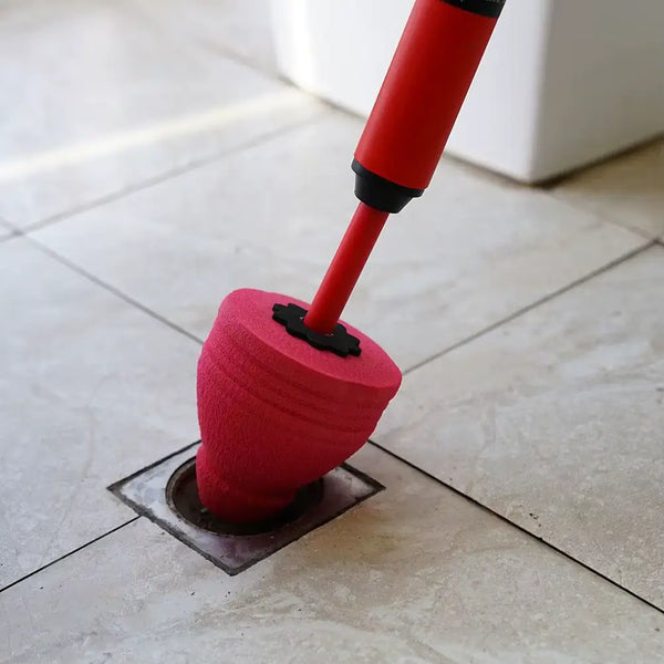 Tapón sellador del destapador apoyado sobre un sifón de piso en un baño